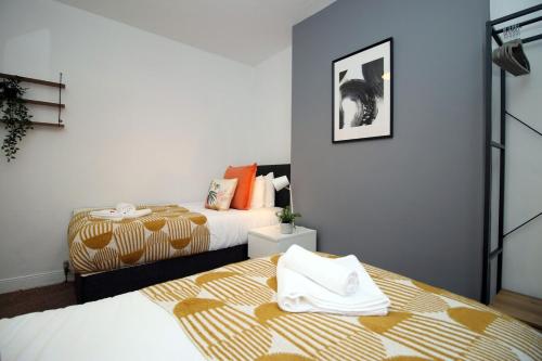 a bedroom with two beds and a picture on the wall at Adamsdown Lodge by Tŷ SA in Cardiff