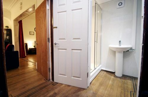 ein Badezimmer mit einer weißen Tür und einem Waschbecken in der Unterkunft Flora Suites by Tŷ SA in Newport