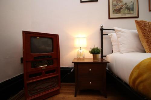 ein Schlafzimmer mit einem Bett und einem TV in einer Kommode in der Unterkunft Flora Suites by Tŷ SA in Newport