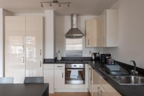 a kitchen with white cabinets and a sink at GuestReady - London Urban Retreat at East End in London