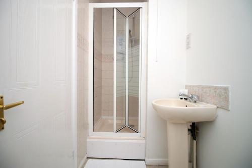 ein Bad mit einer Dusche und einem Waschbecken neben einer Tür in der Unterkunft Langstone Close by Tŷ SA in Llanwern