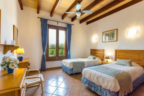a bedroom with two beds and a desk and a window at Finca Domingo in Portopetro