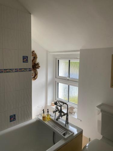 a bathroom with a sink and a tub and a window at Hollyhocks in Saint Minver