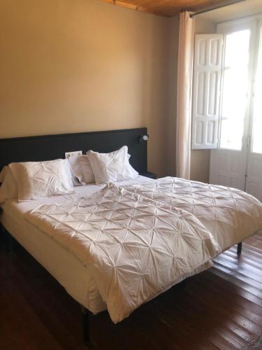 a bed with white sheets and pillows in a bedroom at Pension Casa Simon in Tríacastela
