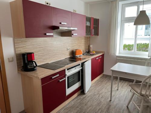 una pequeña cocina con armarios rojos y una mesa en Villa Victoria mit Meerblick, en Sassnitz