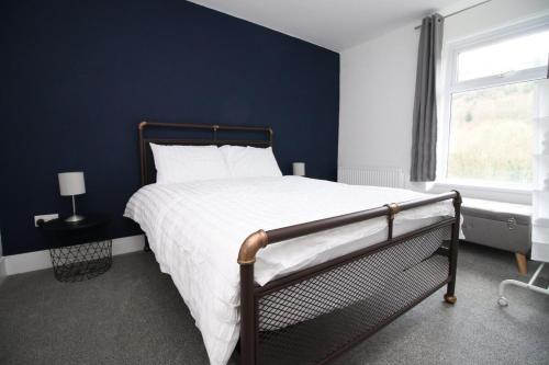 ein Schlafzimmer mit einem großen Bett mit blauer Wand in der Unterkunft Station Terrace by Tŷ SA - 3 Bed in Mountain Ash in Quakers Yard