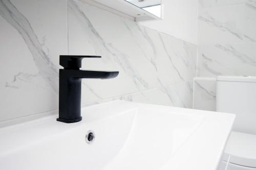 a bathroom with a black faucet on a white sink at Station Terrace by Tŷ SA - 3 Bed in Mountain Ash in Quakers Yard