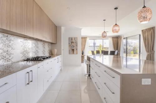 NorthfieldModern Mansion in Lightsview By Host Solutions的白色的厨房配有白色橱柜和厨房岛