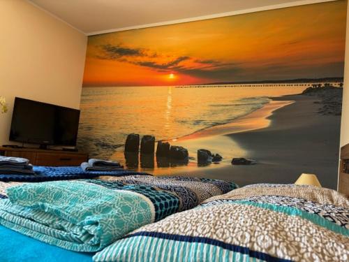 two beds in a bedroom with a mural of a beach at Apartament z Tarasem in Ustka