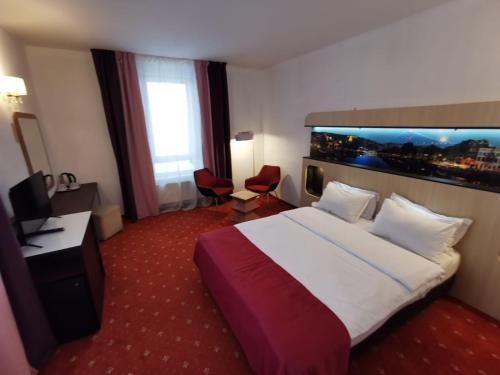 プレデアルにあるAtrium Panoramic Hotel & Spaの大きなベッドとデスクが備わるホテルルームです。