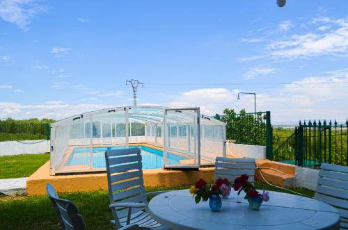 a table with chairs and a glass house with a pool at Casa rural en Casas de Moya 'Casa del Pino Gori' 