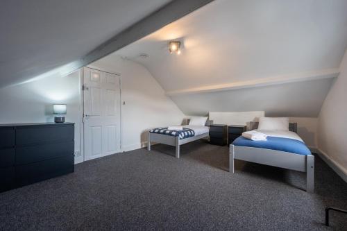 a attic room with two beds and a dresser at Maindee Parade by Tŷ SA in Newport