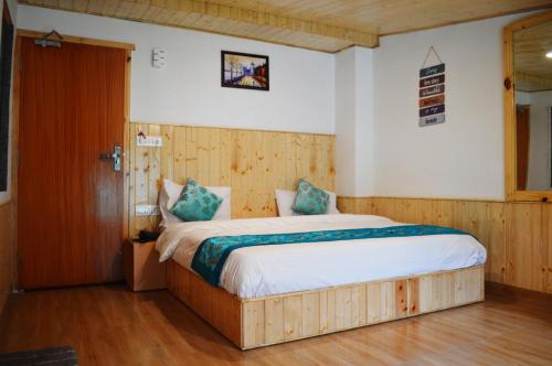 a bedroom with a large bed and a wooden door at Manali Outdoor Retreat by Sheosante in Manāli