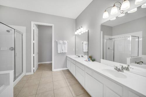 La salle de bains blanche est pourvue de 2 lavabos et d'un grand miroir. dans l'établissement Vista Cay 81 by Top Villas, à Orlando