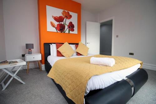 a bedroom with a large bed with an orange wall at Stunning sea views - Barry's Retreat by Tŷ SA in Barry