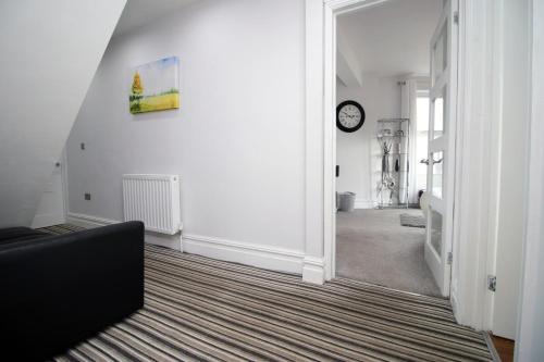 uma sala de estar com um sofá e um relógio na parede em Stunning sea views - Barry's Retreat by Tŷ SA em Barry