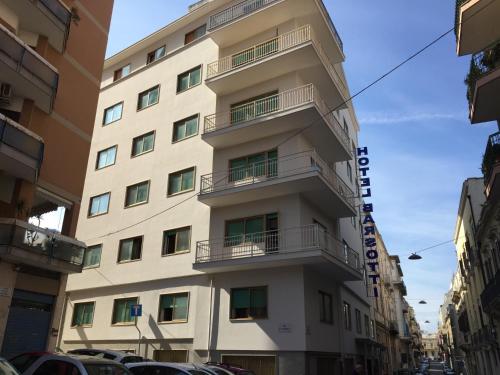 un grand bâtiment blanc avec balcon dans une rue dans l'établissement Hotel Barsotti, à Brindisi