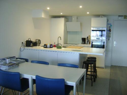 a kitchen with white cabinets and blue chairs and tables at Appartement Corniche II - Superbe Vue Mer !!! wir sprechen flieBen deutsch, Touristentipps, we speak English in Concarneau