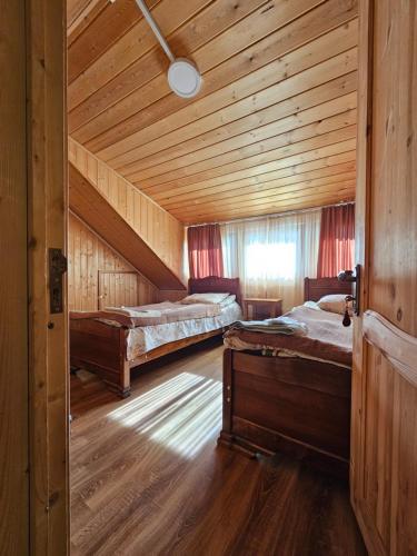 a bedroom with two beds in a wooden cabin at Guesthouse Ushguli Maspindzeli in Ushguli