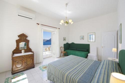 een slaapkamer met een bed en een groene bank bij Villa Panorama in Praiano