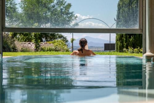 a woman is sitting in a swimming pool at Il Falconiere Relais & Spa in Cortona