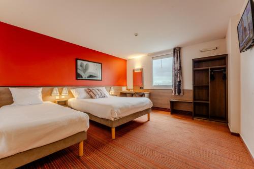 Cette chambre comprend 2 lits et un mur rouge. dans l'établissement Ace Hotel Arras-Beaurains, à Beaurains