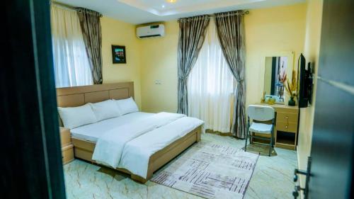 a bedroom with a large bed and a desk and window at Exquisite luxurious 2 bedroom Apartment. in Gwarinpa