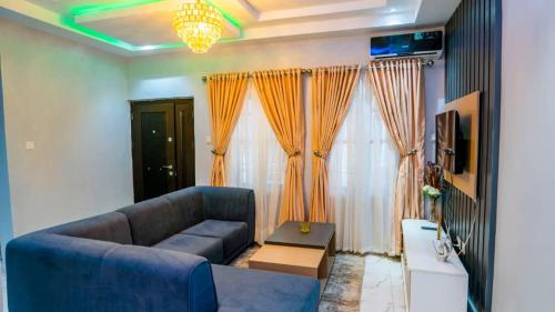 a living room with a blue couch and orange curtains at Exquisite luxurious 2 bedroom Apartment. in Gwarinpa
