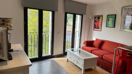 a living room with a red couch and sliding glass doors at LOFT URBANO in Béjar