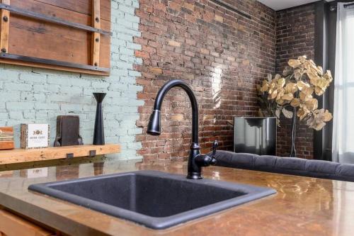 a sink in a kitchen with a brick wall at Cityscape Elegance - Stylish Skyline Views Retreat in Bangor