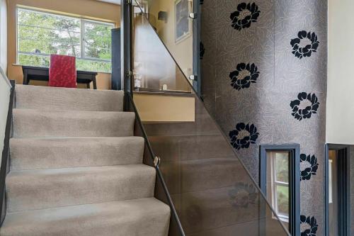 a staircase in a house with a red chair at Villa 10 min bus to Oxford train in Oxford