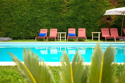 four chairs and an umbrella next to a pool at Hôtel La Perna in Pernes-les-Fontaines