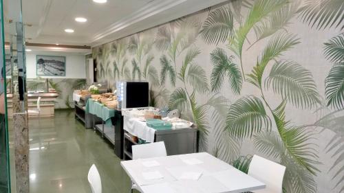 a restaurant with tables and chairs and a wall with leaves at Hotel Las Vegas in Benidorm