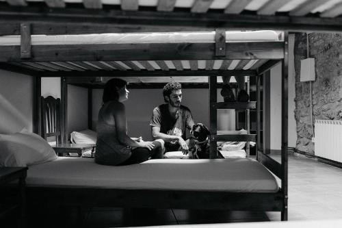 a man and a woman sitting on a bed with a dog at El Refugi in Arboli