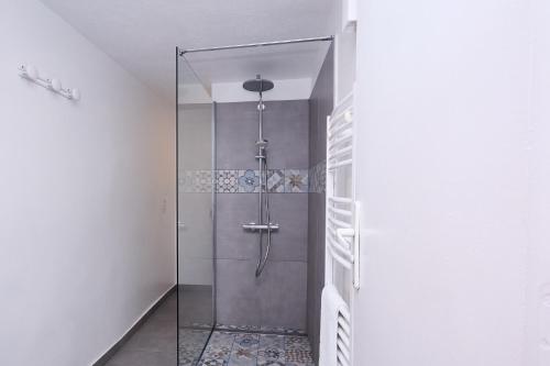 une douche avec une porte vitrée dans une salle de bain dans l'établissement Appartements avec jardin dans Villa Rocaille, à Cassis