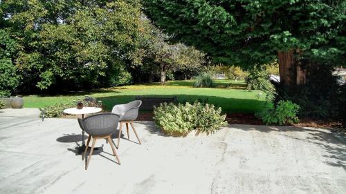 eine Terrasse mit einem Tisch und Stühlen sowie einem Park in der Unterkunft Demeures ressourçantes - Le Vallon in Saint-Martin-de-Saint-Maixent