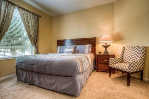 een slaapkamer met een groot bed en een stoel bij Vista Cay 44 by Top Villas in Orlando