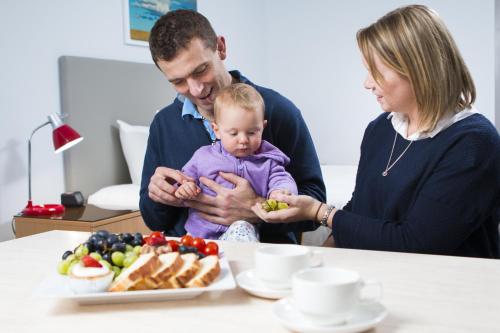 a man and woman holding a baby and a plate of food at Altitude Motel Apartments in Toowoomba