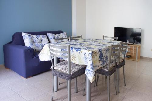 a dining room table with chairs and a blue couch at Casa Rosa sul Mare in Capo dʼOrlando