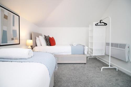 a white bedroom with two beds and a radiator at The White House by Tŷ SA - Zip World & Bike Park in Aberdare
