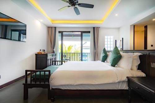 a bedroom with a large bed with a ceiling fan at Manyo Hotel and Resort in Luang Prabang