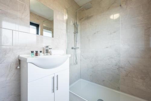 a white bathroom with a sink and a shower at Trinity View by Tŷ SA - Beautiful 5 bed in Newport in Caerleon
