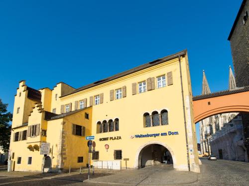 un bâtiment jaune avec une arche dans une rue dans l'établissement ACHAT Hotel Regensburg Herzog am Dom, à Ratisbonne