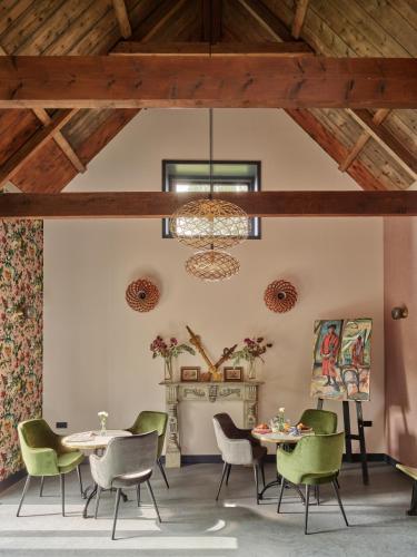 a dining room with green chairs and a ceiling with a chandelier at B&B De Pastorie bij Dokkum in Reitsum