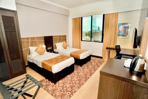 ein Hotelzimmer mit 2 Betten und einem Schreibtisch in der Unterkunft REGALPARK Hotel Kuala Lumpur in Kuala Lumpur