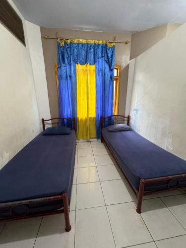 two beds in a room with a window at Horas Hotel in Sibolga