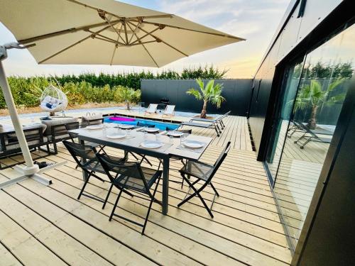 - une table avec des chaises et un parasol sur une terrasse dans l'établissement Evasion tropicale, à Bretteville-sur-Odon