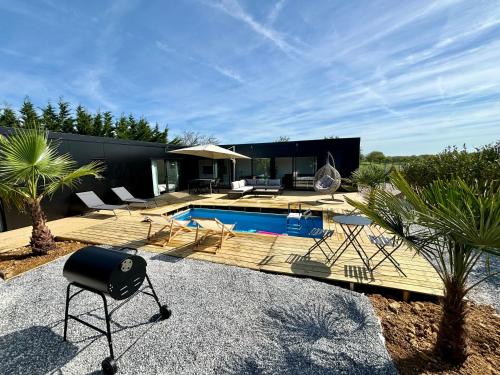 une arrière-cour avec une piscine et une maison dans l'établissement Evasion tropicale, à Bretteville-sur-Odon