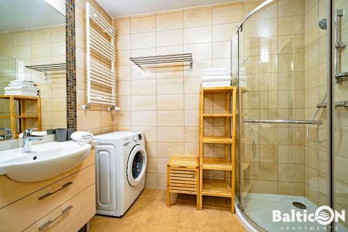 a bathroom with a sink and a washing machine at Apartamenty BalticON Polanki in Kołobrzeg
