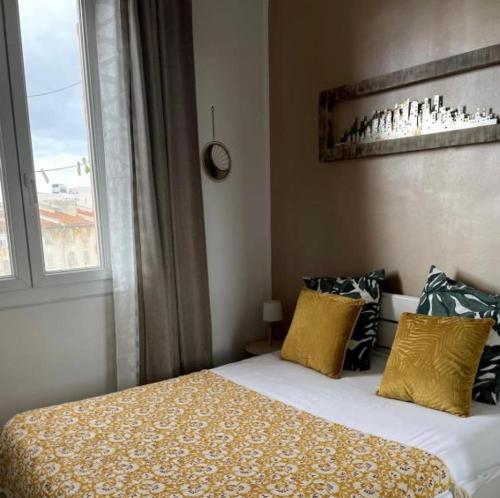 une chambre avec un lit avec des oreillers jaunes et une fenêtre dans l'établissement Appartements Lumineux, à Marseille